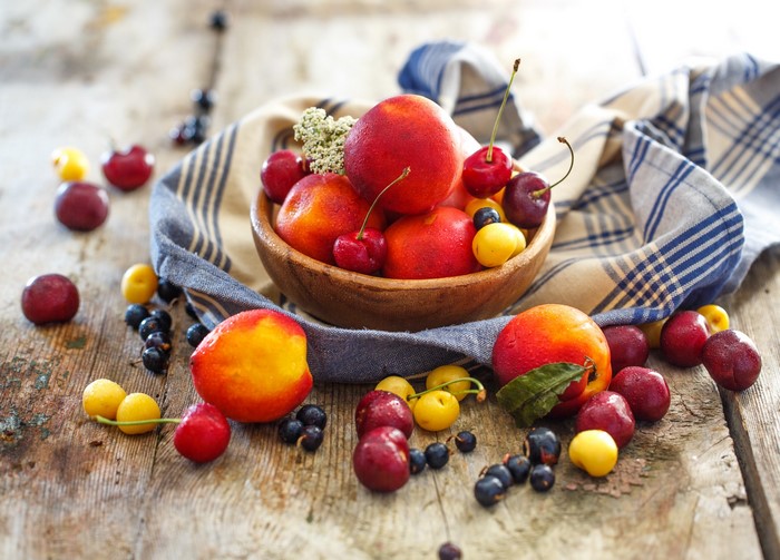 Bowl of peaches, cherries, and berries on a wooden table