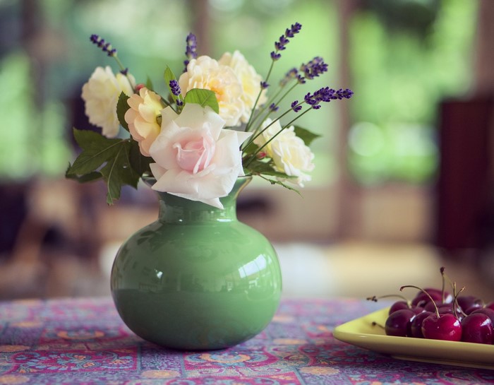 Roses and lavender in a green vase with cherries