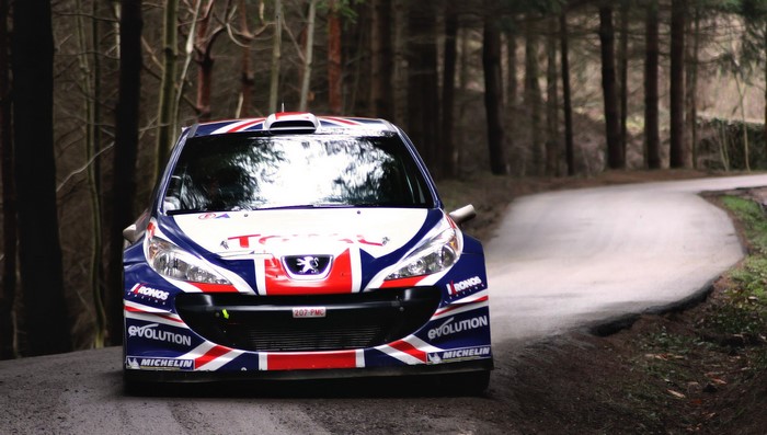 Peugeot rally car with Union Jack livery on a forest road