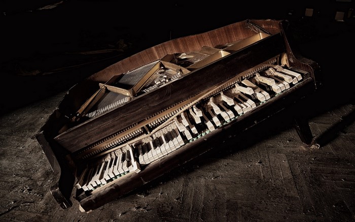 A broken grand piano on a dark floor