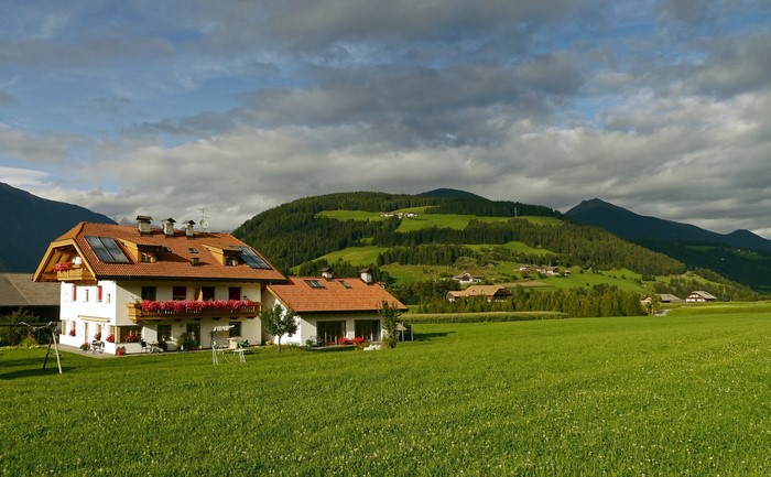 Houses in Valdaora, Italy with mountains and grasslands