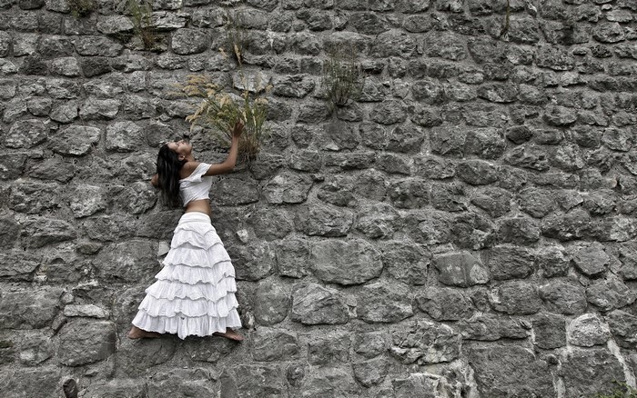 Woman in white dress on stone wall