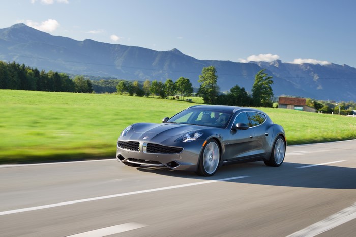 Grey Fisker Karma driving on a road with mountains