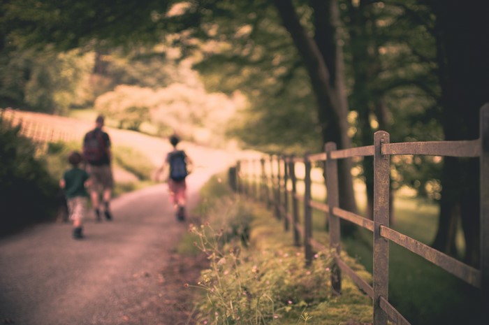 Family walking on a path with a fence