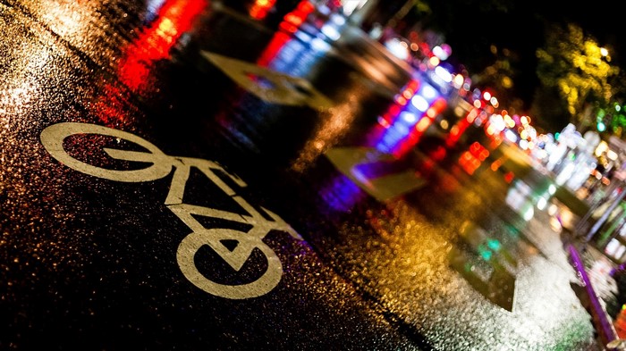 Bicycle lane marking on wet asphalt at night in Paris