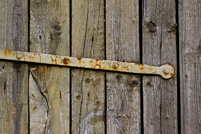 Close-up of weathered wood planks with a rusty hinge