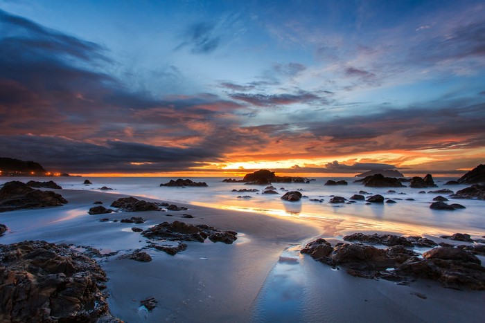 Sunset over a rocky beach with dramatic clouds
