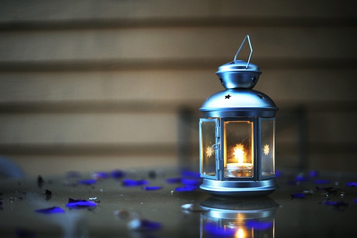Lantern with a lit candle and blue petals