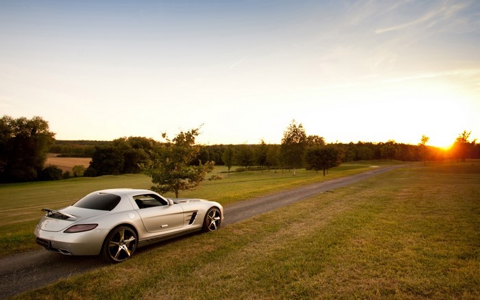 Silver Mercedes-Benz SLS on a dirt road at sunset