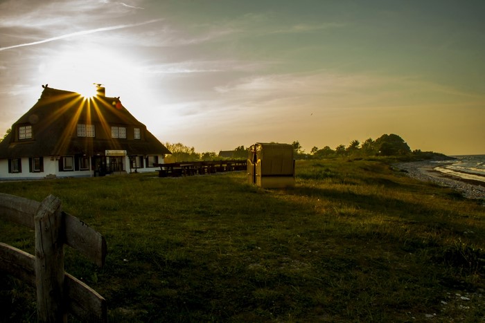 Thatched roof house by the sea at sunset