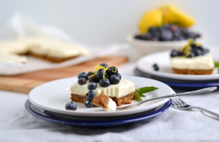 Blueberry cheesecake slices on plates with lemons and blueberries