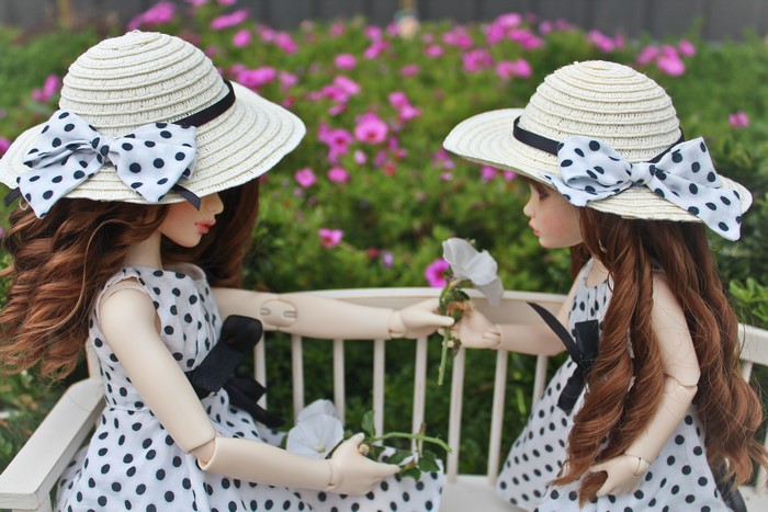 Two dolls wearing hats and polka dot dresses