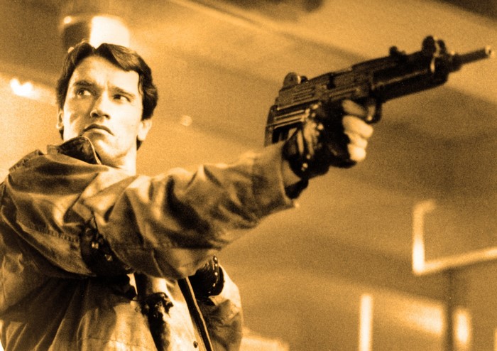 Arnold Schwarzenegger as The Terminator holding a submachine gun