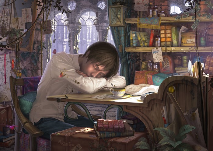 Young man sleeping at a desk with books