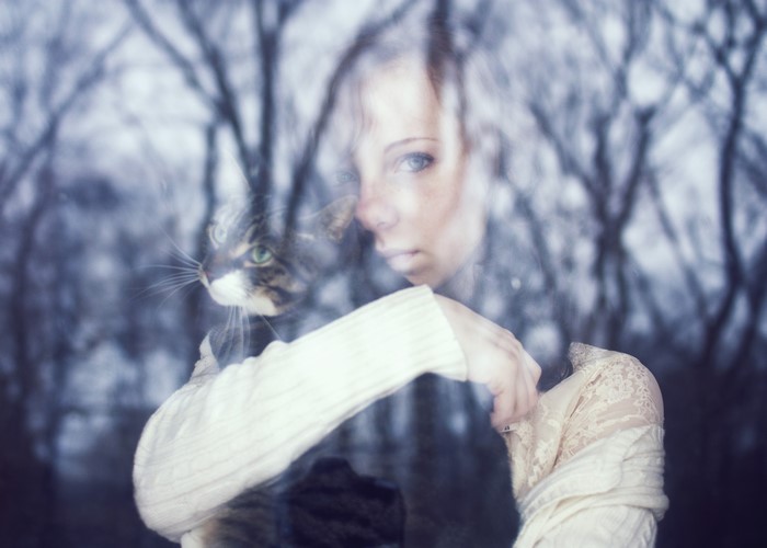 Woman and cat behind glass