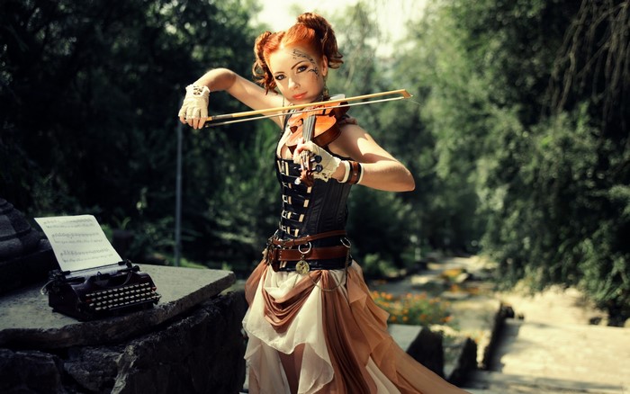 Steampunk redhead girl playing violin near typewriter