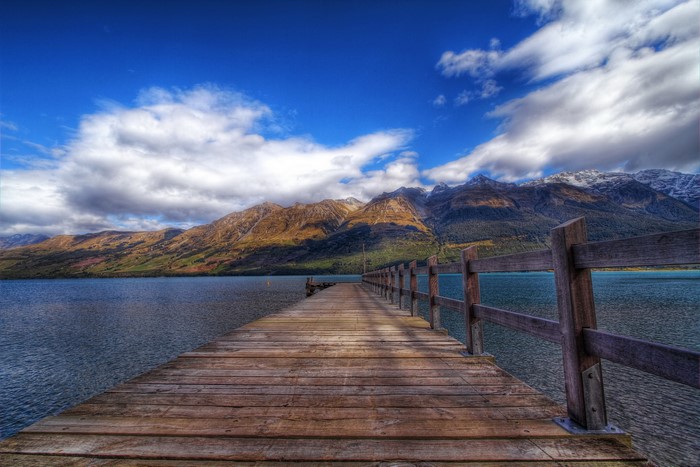 Wooden pier on a lake with mountains and clouds
