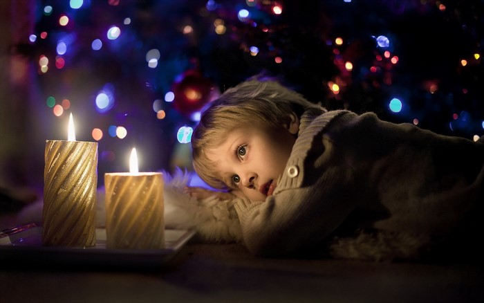 Boy looking at Christmas tree lights and candles