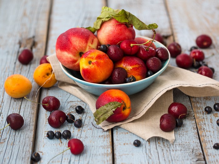 Bowl of Peaches, Cherries, and Apricots on Wooden Table