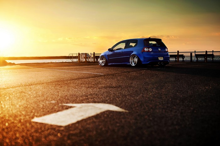 Blue Volkswagen Golf R32 parked by the water at sunset