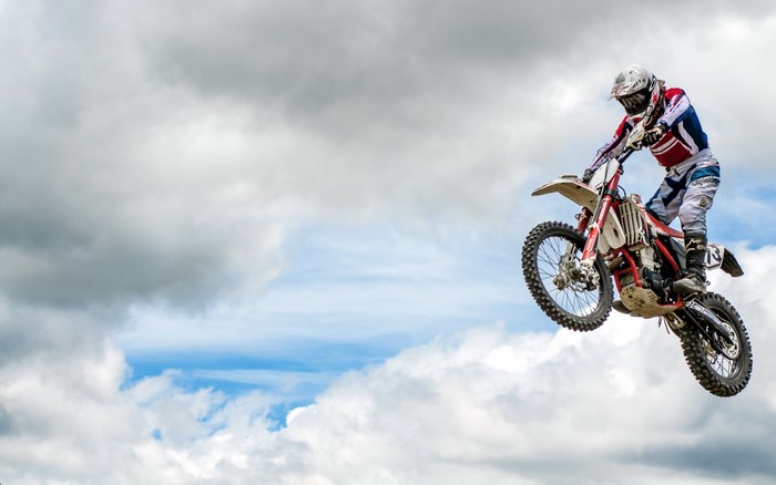 Motocross rider jumping over clouds