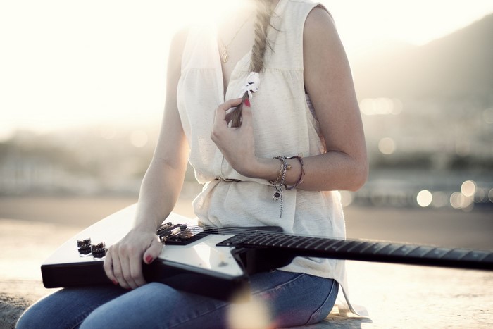 Woman with braided hair holding a guitar