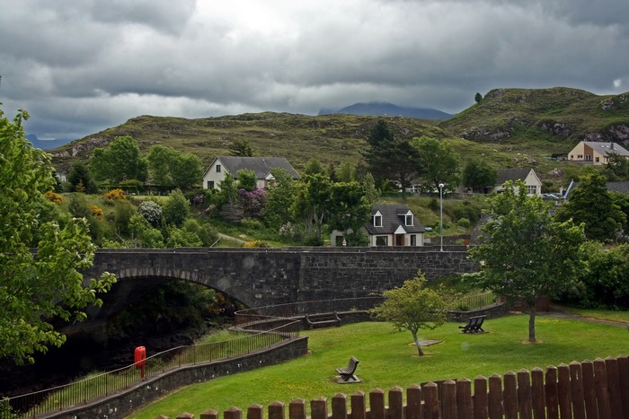 Stone bridge over water with houses and hills in Poolewe, Scotland