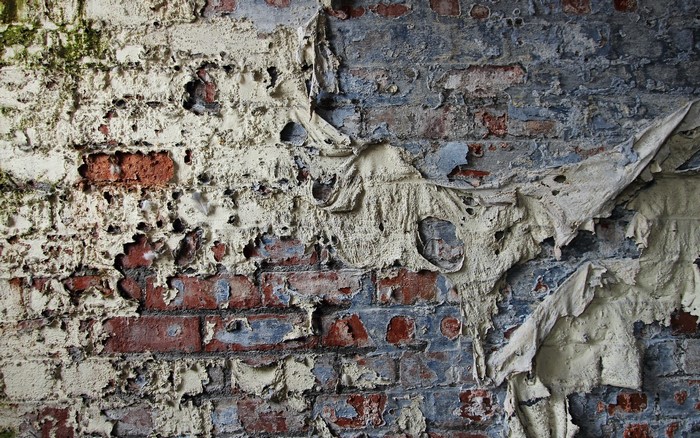 Peeling plaster on a weathered brick wall