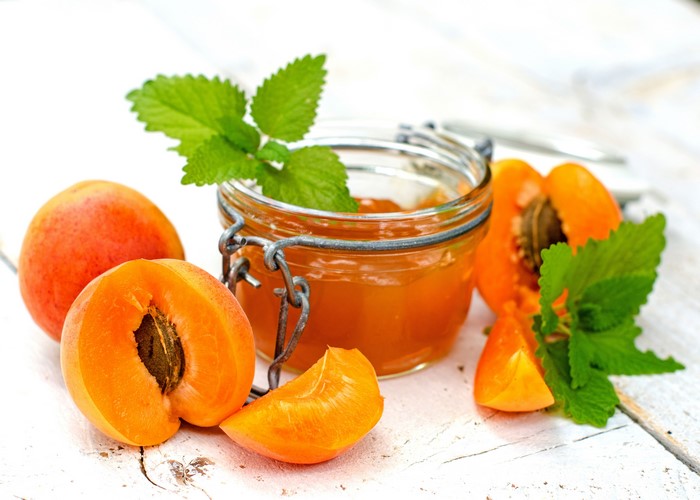 Apricot jam in a jar with fresh apricots and mint