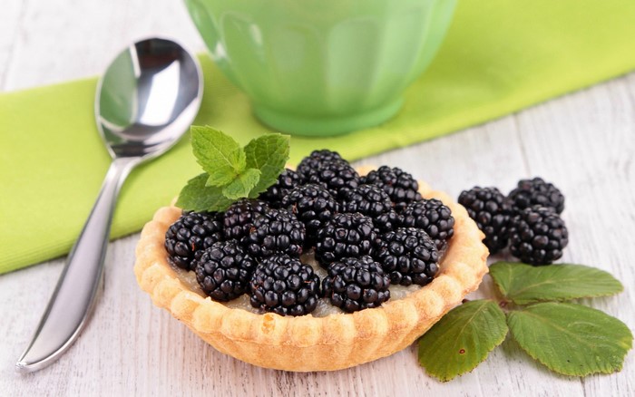 Blackberry tart with a spoon and green cup
