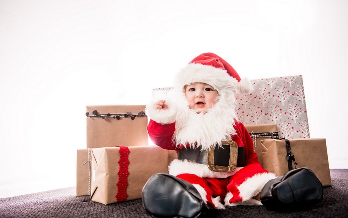Baby dressed as Santa Claus with Christmas gifts