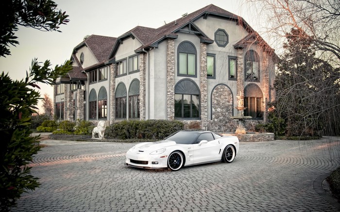 White Chevrolet Corvette parked in front of a mansion