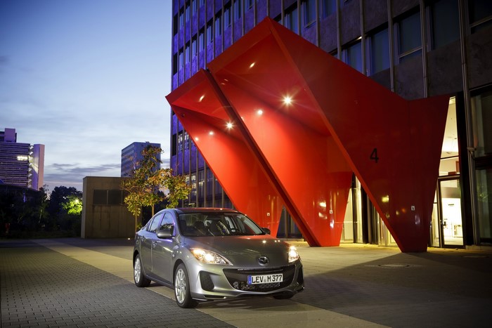 2011 Mazda 3 sedan parked outside modern building