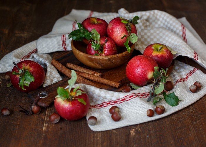 Apples, Cinnamon Sticks, and Hazelnuts on a Wooden Table