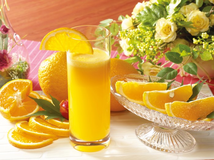 Orange juice in a highball glass with oranges and flowers