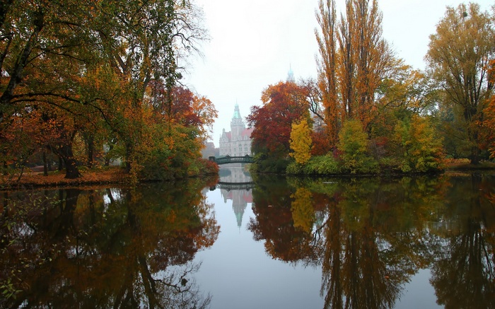 Autumn trees reflected in a lake with a castle in the background