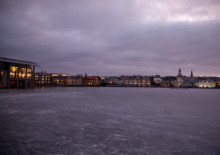 Frozen lake in front of Reykjavik cityscape at dusk
