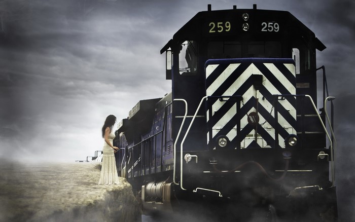Woman in white dress standing next to a train