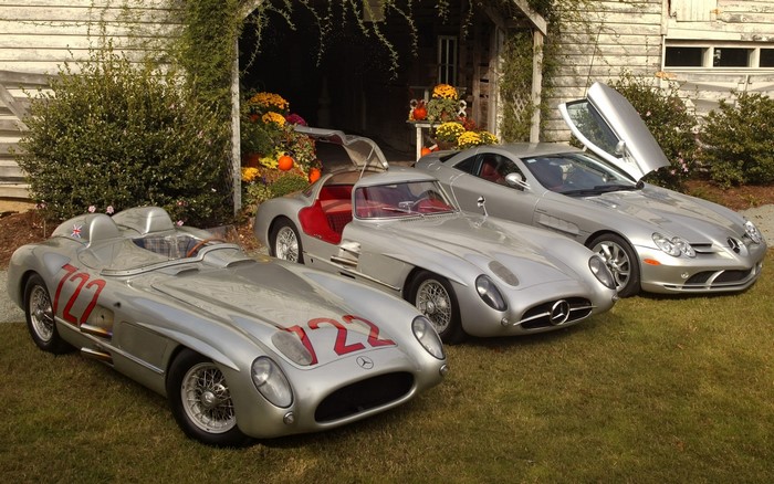 Three Mercedes-Benz SLR cars parked outside a barn