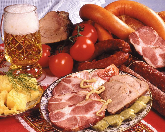 Beer, sausages, meat, and tomatoes on a table