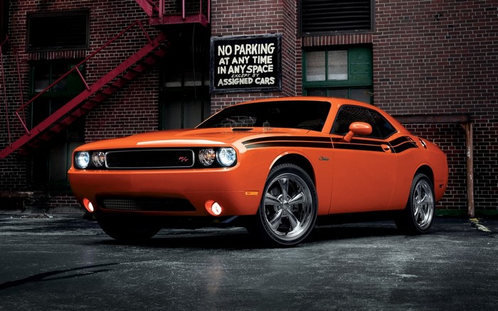 Orange Dodge Challenger R/T parked in front of brick building
