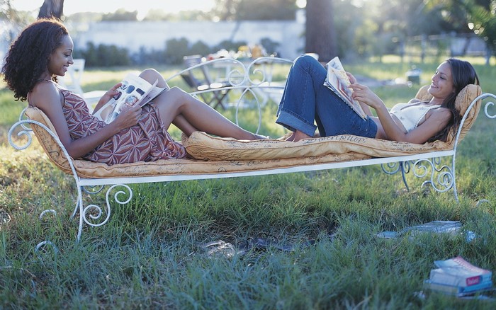 Two women relaxing on a chaise lounge outdoors