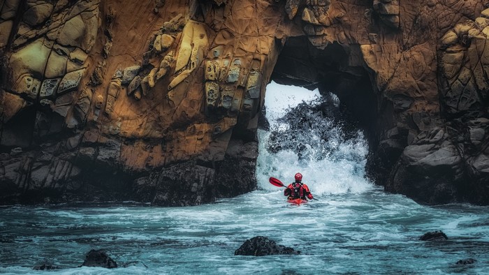 Kayaker entering a sea cave in California