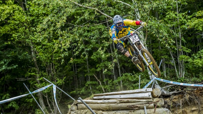 Downhill mountain biker jumps over logs