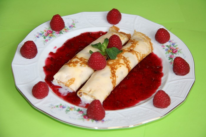 Crepes with raspberry sauce and raspberries on a plate