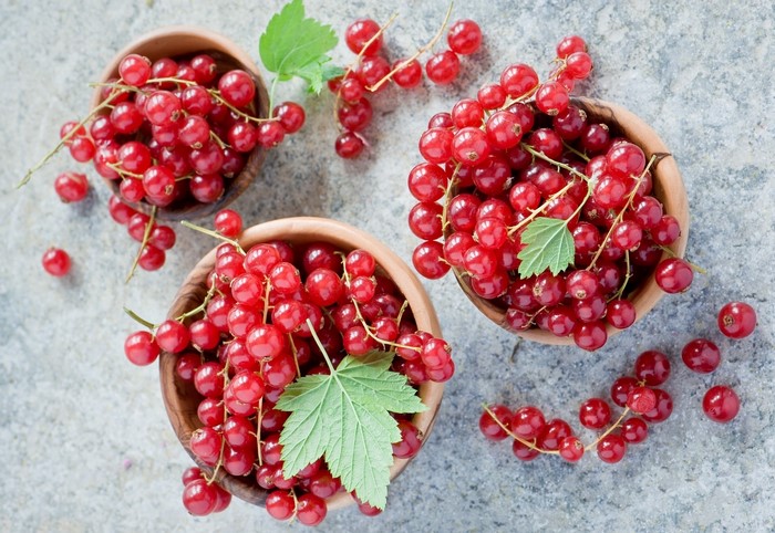 Red currants in wooden bowls with leaves