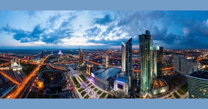 Astana cityscape with modern skyscrapers and Bayterek Tower at dusk