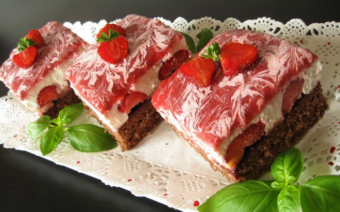 Strawberry chocolate cake slices with cream and basil