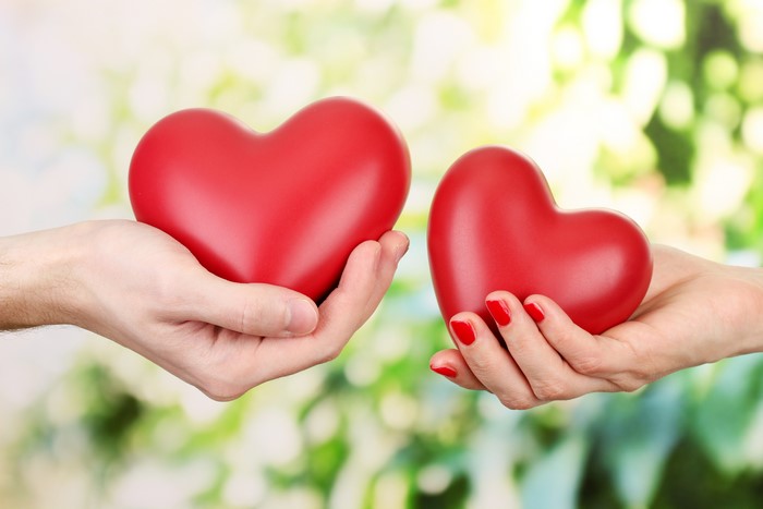 Two hands holding red hearts