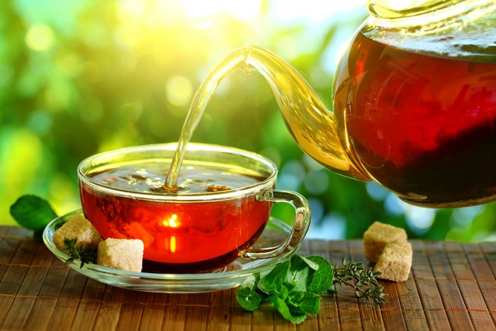 Tea being poured into a cup with sugar cubes